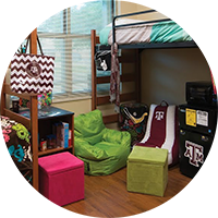 A dorm room with two bunk beds, chairs and other decorations.