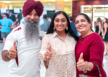 A daughter and her parents all hold up the Gig 'Em thumbs up pose.