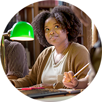 Student sits at a desk in a library.